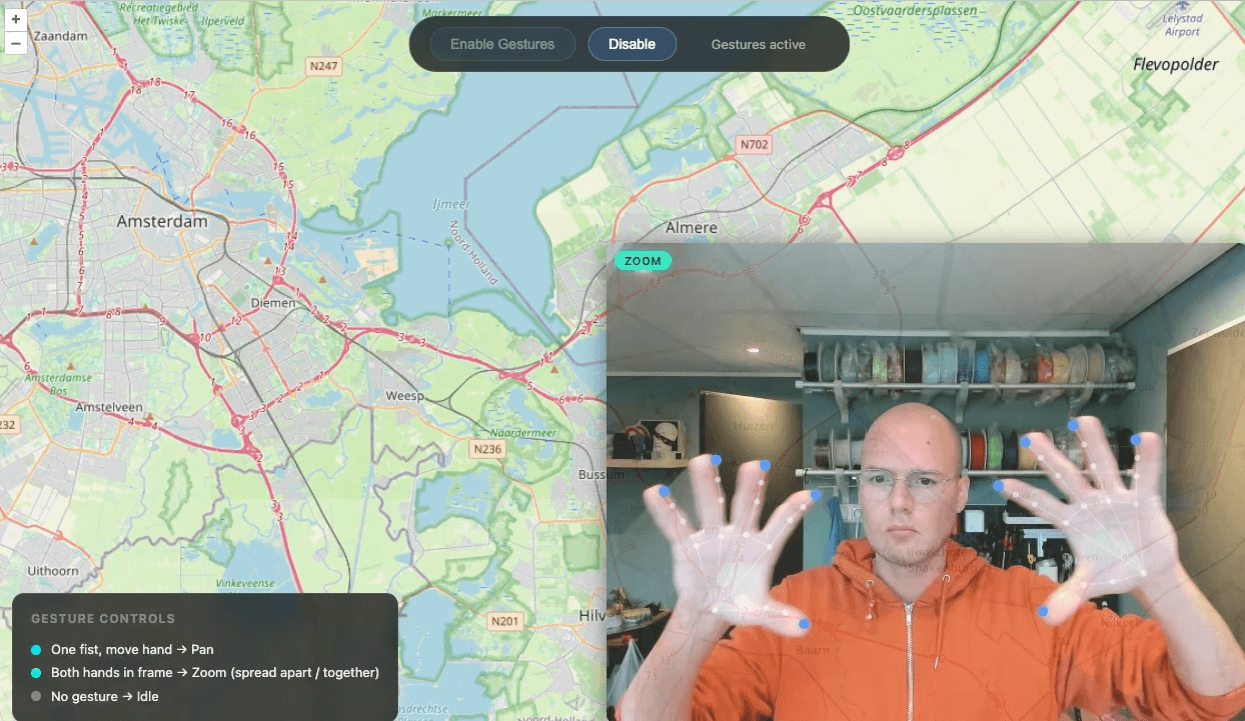 Screen recording of the map gesture control demo showing an OpenLayers map with a small webcam preview in the corner. A user pans the map by making a fist and moving their hand, then zooms by spreading two open hands apart. All hand tracking and gesture detection runs in the browser using MediaPipe WASM with no backend.